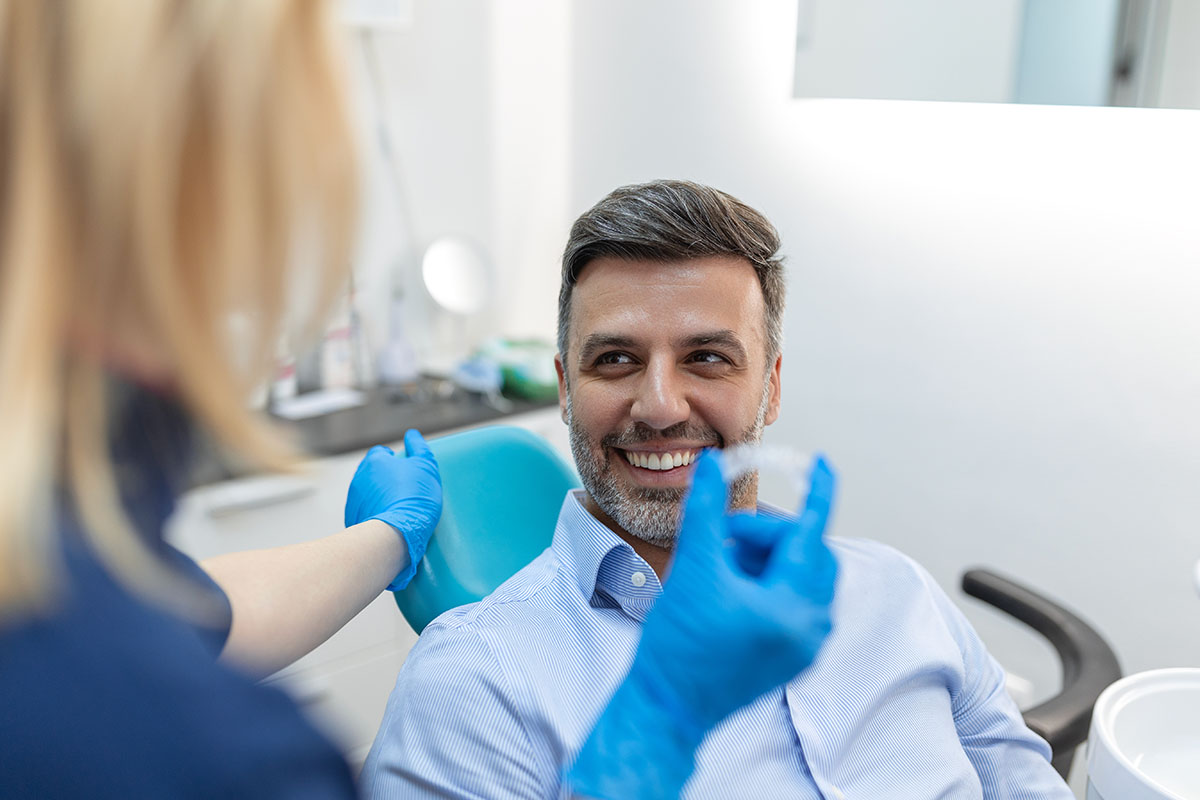 Mann in Zahnarztpraxis bekommt seine Invisalign-Zahnschiene
